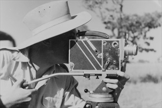 Filming for the Central African Film Unit. A European cameraman operates a movie camera on location