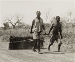 Smoothing corrugations in a road. Two men smooth over corrugations in a road by dragging a section