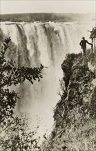 Overlooking Victoria Falls. A man stands on the edge of a cliff overlooking Victoria Falls, a