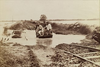 Without a paddle. Three men attempt to cross a flooded section of railway line on a small,