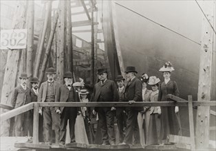 Sir Alfred Holt at a dockyard. A group of formally dressed men and women pose for the camera beside