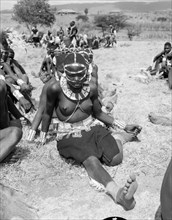 Portrait of a female Wakamba dancer. A semi-naked female Wakamba dancer sits on the ground, leg