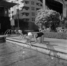 Olympic swimmers dive in. Two female swimmers competing in the 1956 Olympic Games are captured