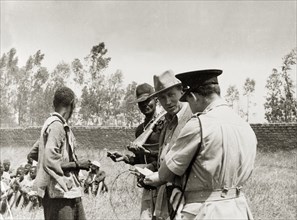 Searching for Mau Mau suspects. A farmer and military officers question a Kikuyu farm labourer.