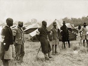 Kikuyu Home Guards in camp. Six Kikuyu Home Guards, dressed in makeshift uniforms and armed with