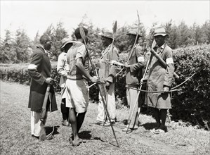 Kikuyu Home Guards. An official photograph of six Kikuyu Home Guards, armed with spears and bows