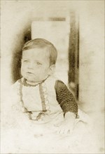 Portrait of a baby, Australia. Portrait of a baby dressed in a pinafore and knitted top aged around
