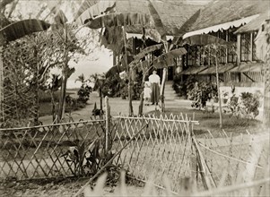 Bungalow garden on the Andaman Islands. A woman and child identified as 'Marjory and Mother' wander