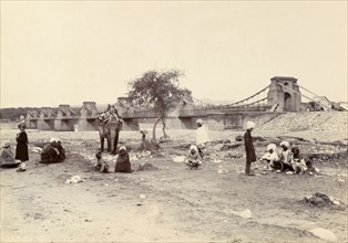 The entrance to Kashmir. A group of men with an elephant wait near a river bridge at the entrance