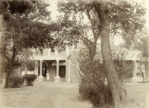 Officer's bungalow, Pindi. View through the trees of a uniformed Indian servant at the columned