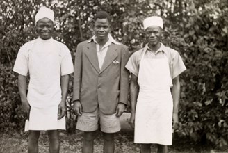 Domestic servants. Three domestic servants in workwear smile for the camera, their roles identified