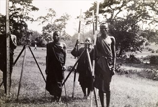 Maasai men help a surveying team. Four Maasai men in traditional dress help a surveying team by
