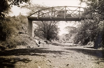Hal Wallhouse's bridge. A motorcar drives across a small bridge that spans a dried up watercourse.