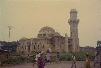 Mosque at Okene. Passers-by near a mosque at Okene. Okene, Nigeria, circa 1964. Okene, Kogi,