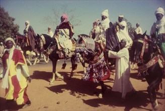 Decorated horses, Nigeria. Men dressed in ceremonial attire ride horses decorated with tassles and
