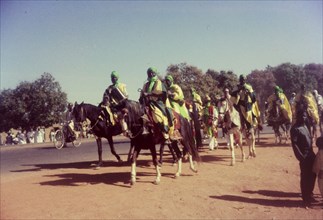 Procession for Ramadan. A group of Nigerian men dressed in ceremonial attire ride horseback in a
