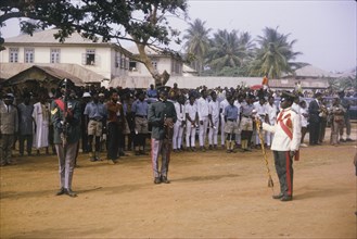 Fajuyi's state funeral. Uniformed military men perform a salute in front of crowds gathered for the
