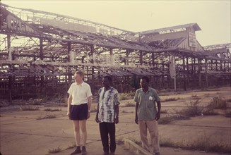 The remains of Onitsha market. Three men stand in front of the skeletal remains of the old market