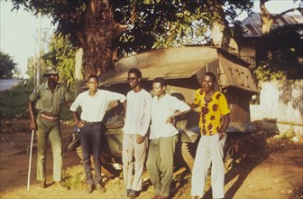 Damaged tank in Onitsha. Five young men pose for the camera, leaning against an armoured tank that