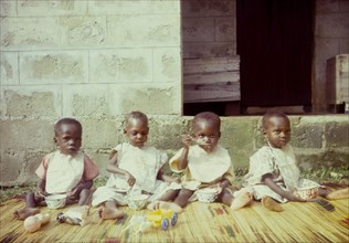 Orphans at a Church of Nigeria hospital. Four young orphans, seated on a rush mat, feed themsleves