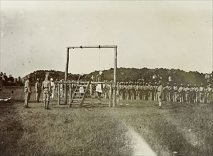 Colonial execution. The bodies of two African men hang from a wooden scaffold, their execution