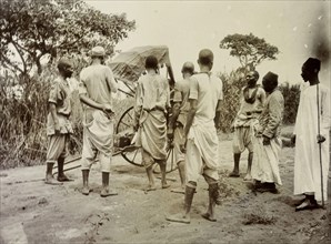 Broken rickshaw, Uganda. A group of African servants consider what to do with rickshaw that has
