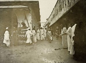 Zanzibar 'business quarter'. Men in long robes walk purposefully along a busy, narrow road in the