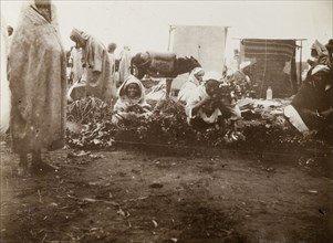 Market scene, Casablanca. Street traders crouch on the ground, trying to sell fruit and vegetables