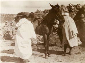 Loading up a mule, Morocco. Two Moroccan men load up their mule with blankets and baskets at a