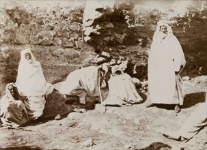Group of Morrocan men. A group of Moroccan men dressed in white robes rest at a ruin in the desert.