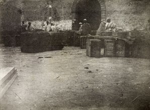 Hunter's store'. Moroccan men congregate around several large crates placed on the ground.
