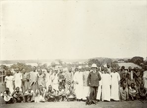 Tsetse fly researchers. A European official poses with Africans in a variety of costumes. A caption