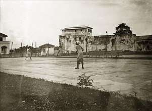Kenyan servants playing tennis. Two African boys play tennis on a court begind Fort Jesus, part of