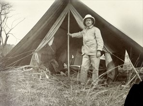 Frederick Stanbury outside a tent. Frederick Stanbury poses for the camera in front of a small,