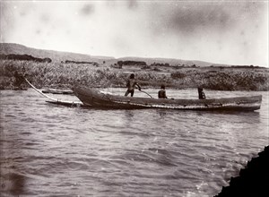 Canoe made with no nails. Three African men pilot a large wooden canoe on Lake Victoria. According