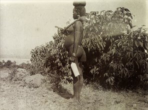 Kavirondo woman. Profile shot of a naked Kenyan woman carrying a bottle of milk on her way to a