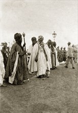 The Emir of Zaria. The Emir of Zaria, dressed in fine robes, holds a staff as he parades with a