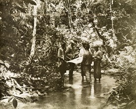 Surveying in the Kenering Valley.. A European surveyor and his Malay assistants, part of a