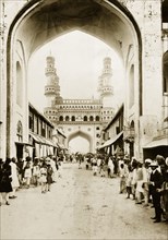 The Char Minar in Hyderabad. Pedestrians line a street running towards the Char Minar. Hyderabad,