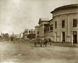 Strand Road in Rangoon. Pedestrians and cattle-drawn carts meander along Strand Road. Rangoon