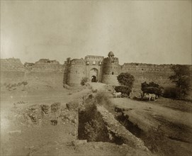 Ruined walls in Delhi. Cattle-drawn carts laden with hay stand outside the ruined walls in an old