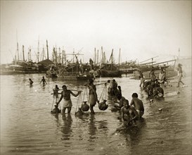 Calcutta water carriers. Water carriers fill their pitchers on the banks of the Hooghly River. The
