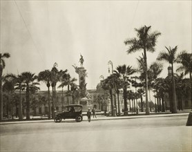 Monument in a piazza, Lima. Palm trees surround a tall stone monument decorated with sculptures in