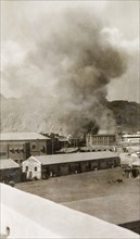 Riot damage in Aden, 1947. A large plume of smoke billows from a building in the Jewish quarter of