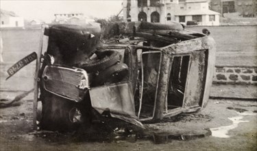 Car destroyed by Arab riots in Aden, 1947. A burnt-out car lies on its side in a street in Aden,