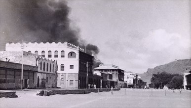 Riot damage in Aden, 1947. A plume of black smoke rises from a building in the Jewish quarter of