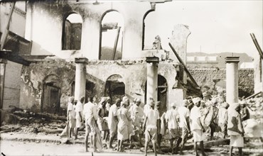 Aftermath of Arab riots in Aden, 1947. A crowd of men gather outside a gutted building in the