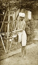 Watering the garden, India. A turbaned Indian man sprinkles water onto a dusty garden from a