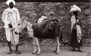 A 'dhobi' and his donkey, India. A 'dhobi' (laundryman), pictured with a donkey laden with bags of