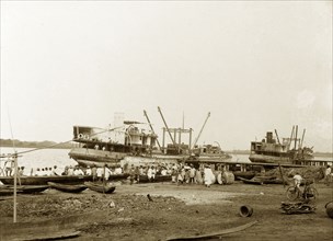 Boats at a Badagry wharf. Two steamers, labelled in manuscript as 'Ife' and 'Ila', are moored at a